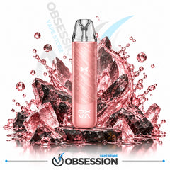 A pink disposable vape device stands upright in front of a stylized cluster of dark crystals and pink liquid splashes on a white background, with Obsession branding visible.