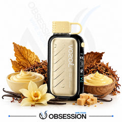 A Vozol Tobacco Flavoring Machine vape device in a gold and black finish, styled with vanilla cream, vanilla beans, tobacco leaves, and tobacco pieces on a white background with the Obsession Wireless Store logo at the bottom.