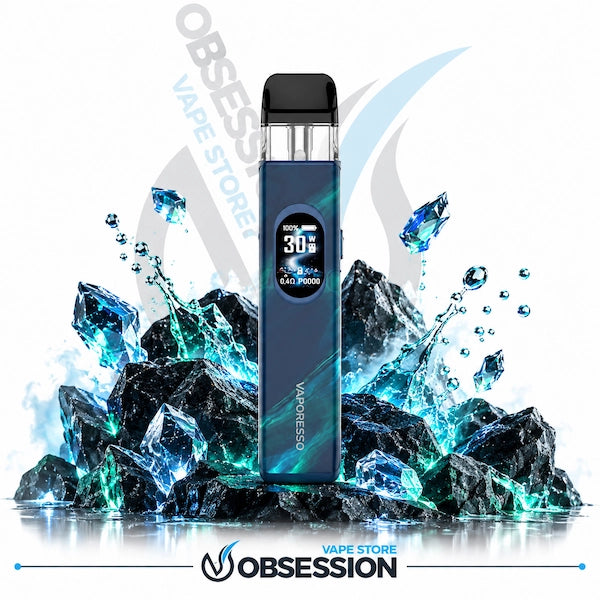 A blue disposable vape device with a digital screen showing 30% battery, standing upright on a reflective surface in front of dark rocks and glowing blue ice crystals. The background is white with Obsession Vape Store branding.