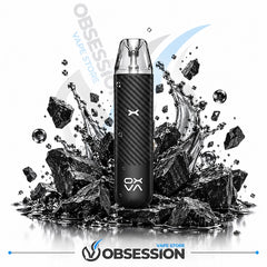 A black carbon-fiber-textured disposable vape device with a clear mouthpiece stands centered on a reflective surface surrounded by black rocks and water droplets. The OBSESSION brand name and logo are visible on the device and as a large watermark/logo behind it, with smaller 'VAPE STORE' text near the bottom.