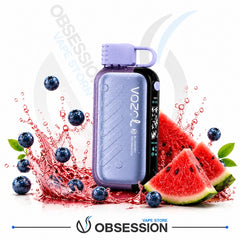 A Vozil disposable vape device in lavender purple and black, surrounded by watermelon slices, blueberries, and red liquid splashes on a white background with Obsession branding.