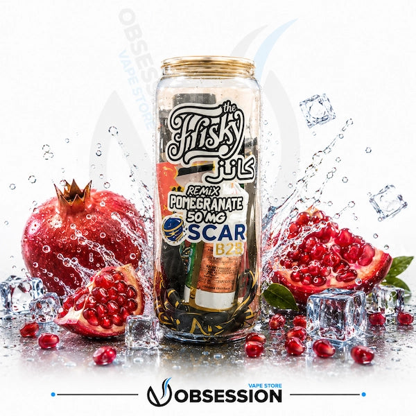 Glass bottle with pomegranate flavoring surrounded by pomegranates and ice cubes on a white background.