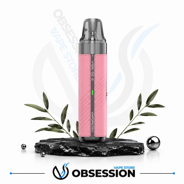 A pink and gray Vaporesso Vape SE 2 disposable vape device displayed on a black marble base with decorative green leaves and metallic spheres, against a white background with Obsession Vape Store branding.