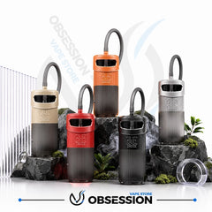 Five disposable vape devices in different colors (beige, orange, red, black, and silver) arranged on rocks with decorative plants and a clear case, with the Obsession Vape Store logo at the bottom.