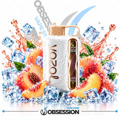 A Vozol vape device with a white body and rose gold metallic accents, surrounded by ice cubes, sliced peaches, and mint leaves on a white background with Obsession branding.