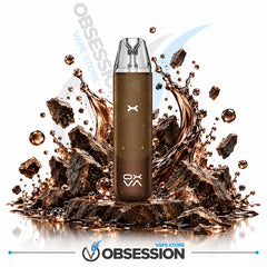 A brown disposable vape device stands upright in front of a stylized splash of dark brown liquid and rock fragments on a white background. The device has a clear mouthpiece and visible OBSESSION branding near the bottom.