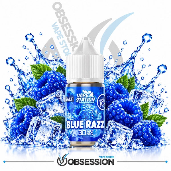 A bottle of Blue Razz Salt Vape Station e-liquid centered against a white background, surrounded by blue raspberries, mint leaves, ice cubes, and water splashes. The bottle label reads 'VAPE STATION', 'BLUE RAZZ', and '30 MG'.